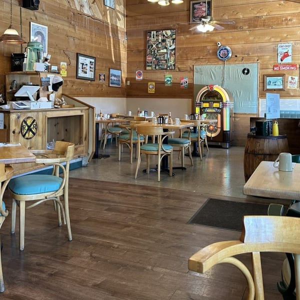 Mother Hubbard's Restaurant interior with wooden walls, tables, chairs, and a jukebox, ready for breakfast.